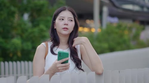 Thoughtful Woman Uses Smartphone in Urban Environment