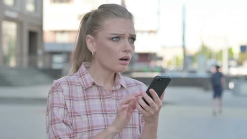 Worried Woman Looking at Smartphone in City