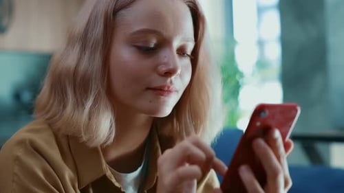 Young Woman Uses Smartphone Device Indoors