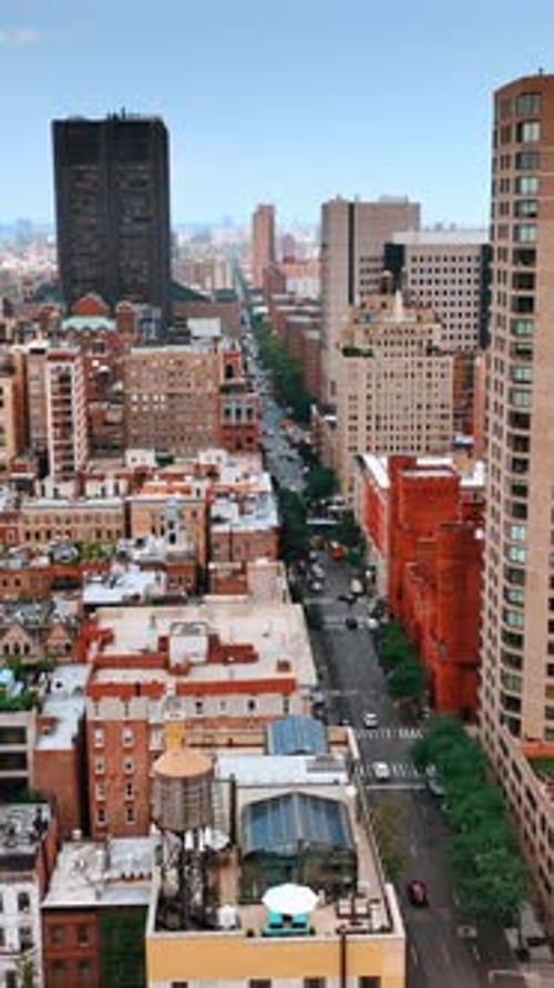 Flying above the tops of low multistoried buildings of New York and long highway.