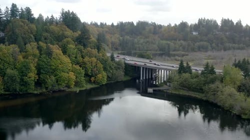 Luftaufnahme von Autos, die auf der Autobahn über einen See mit Bäumen und Wald fahren - Herbstfarben