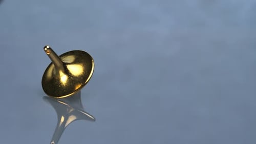 Gold Top Spinning on a Reflective Surface