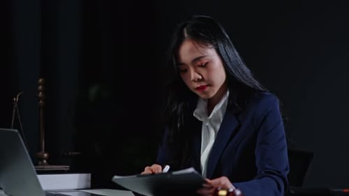 Woman Lawyer Reviews Legal Documents in Office