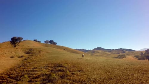 Cowboy On Horseback Traveling On Mountain Range On Sunny Day Slow Motion