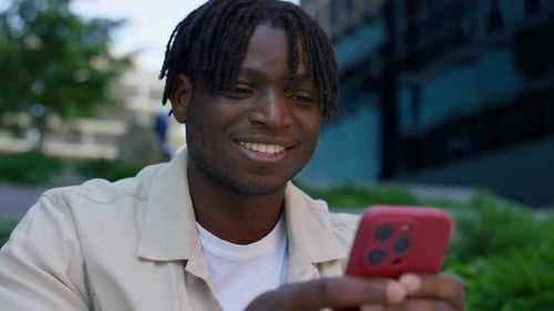 Smiling Young Man Texting on Smartphone
