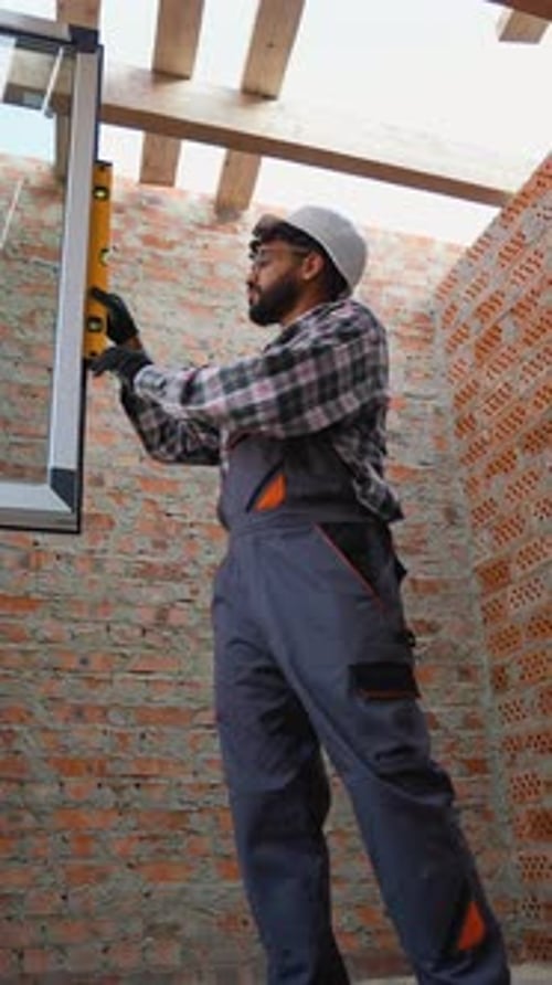 Construction Worker Using Spirit Level to Install Window