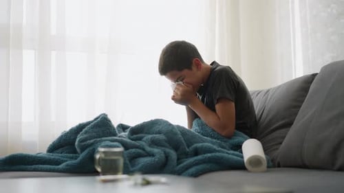 Sick Teenager Blowing Nose on Couch