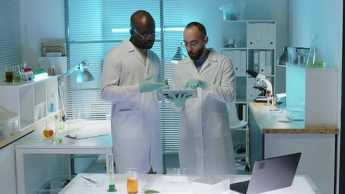 Two Scientists Looking at Tablet Computer and Discussing Research in Lab