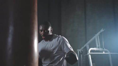 Fitness Workout in Gym Strong African Man Fighter Training Punches with Boxing Bag Healthy Boxer Man