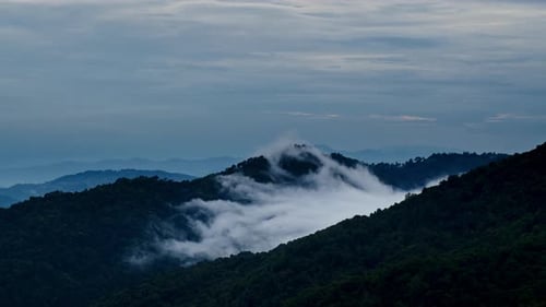 Zeitraffer der weißen Dunstwolke, die sich über dem dunklen Hügel bewegt