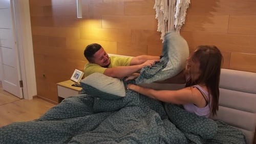 Una pareja joven peleando juguetonamente sobre una cama