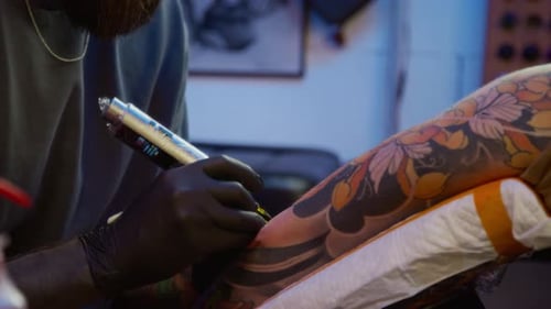 Focused Male Tattooist Using Machine Working in Tattoo Parlor