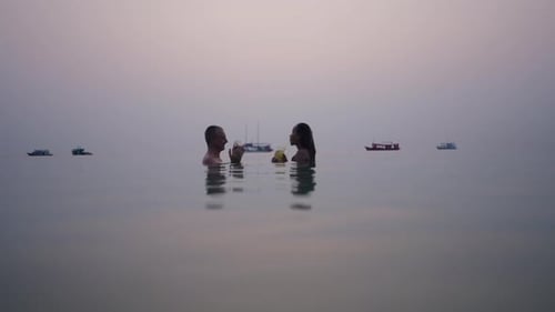 Couple Drinking in Ocean at Sunset