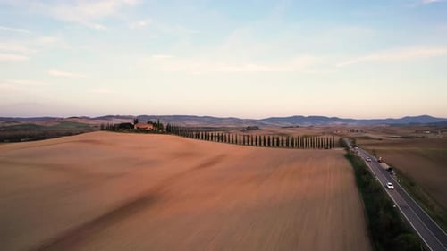 Aerial panorama of Tuscany villa with cypress tree line road at sunset