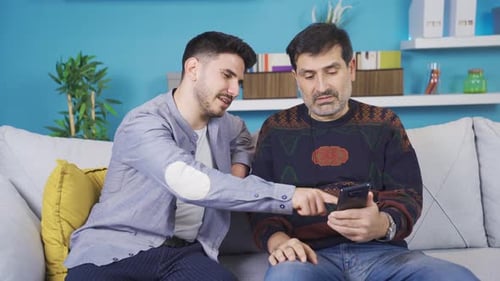 Young Adult Helping Adult with a Smartphone at Home