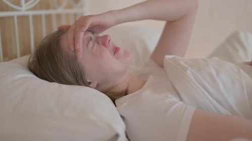Side View of Young Woman with Headache Lying in Bed