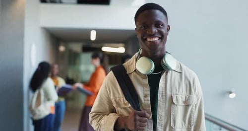 College, hallway and man with headphones, student and happy for education, laughing and scholarship