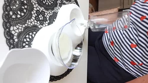 A Woman Is Testing An Online Purchase. Dishes For Cats. She Pours Milk Into A Bowl And Offers It To