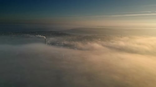 City Smokestack Emitting Smoke Above Thick Fog