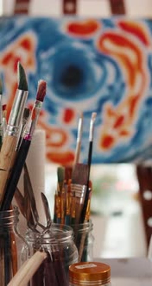 Paintbrushes in Jars with Abstract Painting Background