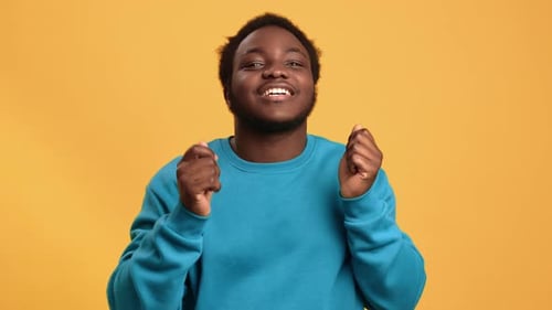 Portrait Funny African Young Guy Smiling Dancing with Positive Emotion Isolated Orange Studio