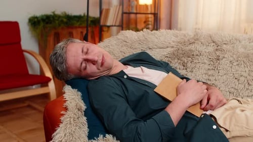 Young Man Falls Asleep Holding Book After Work Day Looking Tired and Ready to Rest and Recharge Mind