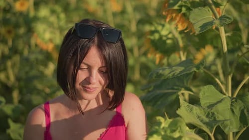 Woman Enjoys Sunflower Seeds Outdoors Brightly Lit Woman Savoring Seeds in Field Pleasurefilled