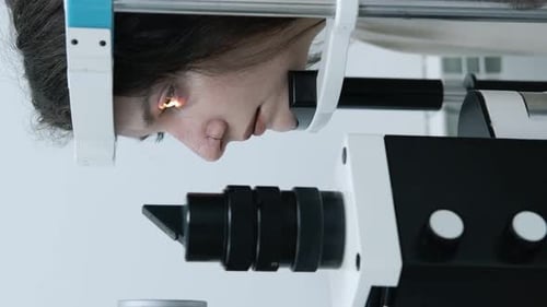 Attentive optometrist examining beautiful female patient with slit lamp in ophthalmology clinic. Opt