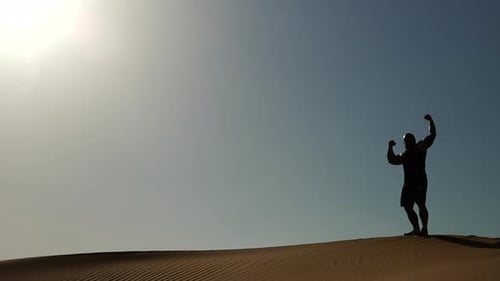 Un bodybuilder fléchit dans le désert de Dubaï