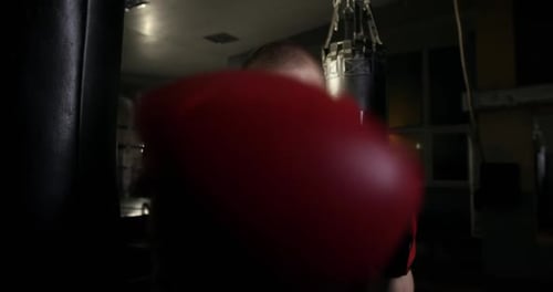 Male Boxer Punching in Gym with Red Gloves