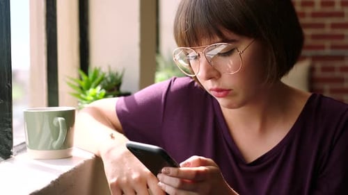 Woman Using Smartphone by Sunny Window