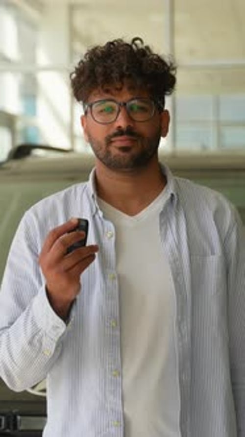 Happy Young Man Showing Car Key in Dealership