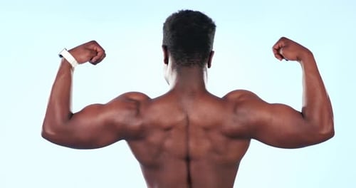 Strong, muscle and black man flexing biceps, bodybuilder in studio with back view