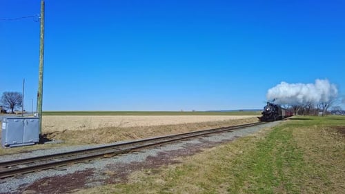 An Approaching Steam Passenger Train Blowing Smoke and Steam on a Sunny Day