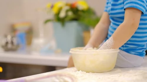 Child Mixing Dough in Kitchen with Adult