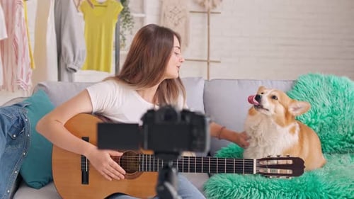 Woman Playing Guitar with Dog In Front of Camera