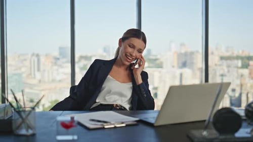 Woman Laughing During Mobile Phone Conversation at Work