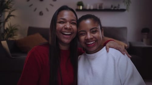 Two Young African American Woman Looking at Camera Happy and Embracing While Being at Home