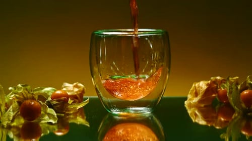 Nahaufnahme des Gießens von Apfelsaft in das Glas, stehend auf einer Glasoberfläche, Tisch, Stockclip, Beeren