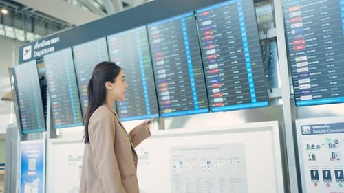 Asian young woman passenger checking depature boarding pass in airport.