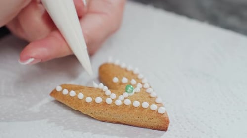 Closeup of Loveshaped Cookie Decorated with White Icing and Green Bead