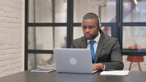 African Businessman with Headset Working on Laptop in Call Center