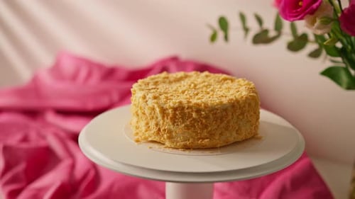 Freshly made delicious puff pastry napoleon cake on a white stand on a background of flowers dessert