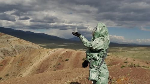 Biologist Environmental Expert in a Protective Suit Holds a Test Tube with Soil for Quality Control