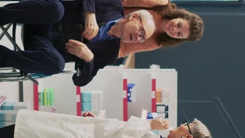 Senior Doctor Consults Patient in Wheelchair with Caregiver