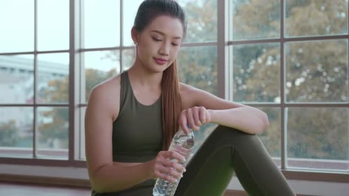 Woman Drinking Water after Exercise in Indoor Setting