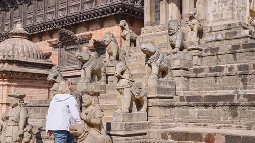 4K Tourist walking up staircase lined with statues, Siddhi Lakshmi Shikara temple, Bhaktapur, Nepal