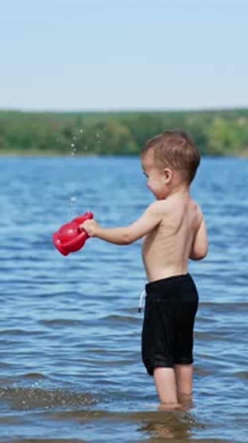 Small funny child playing on river with water. Summer sunny day and splashing on a beach.