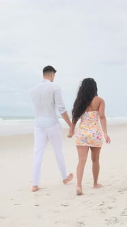 Romantic Couple Walking Hand in Hand on a Sandy Beach