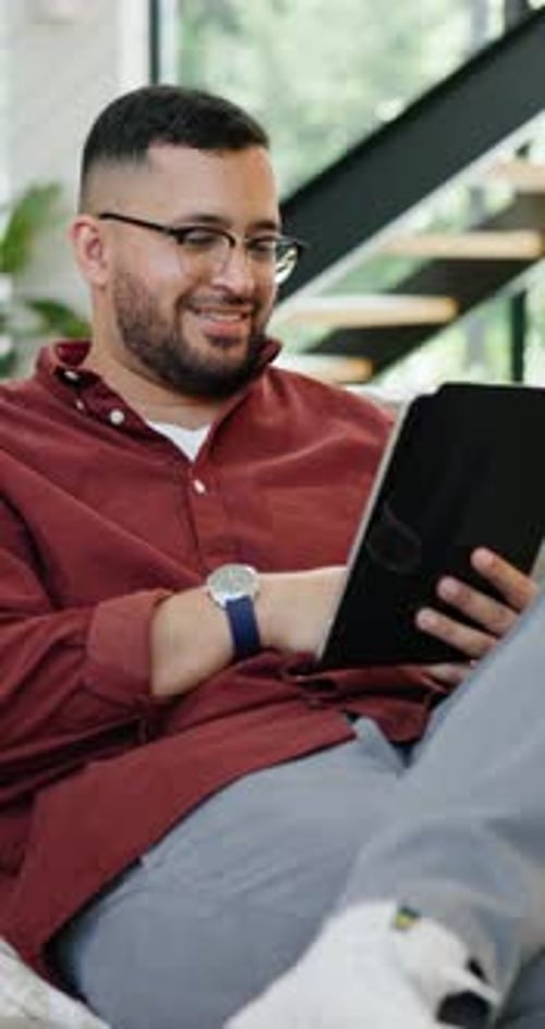 Man, happy and scroll tablet on couch for social media, relax and stream online for video in living